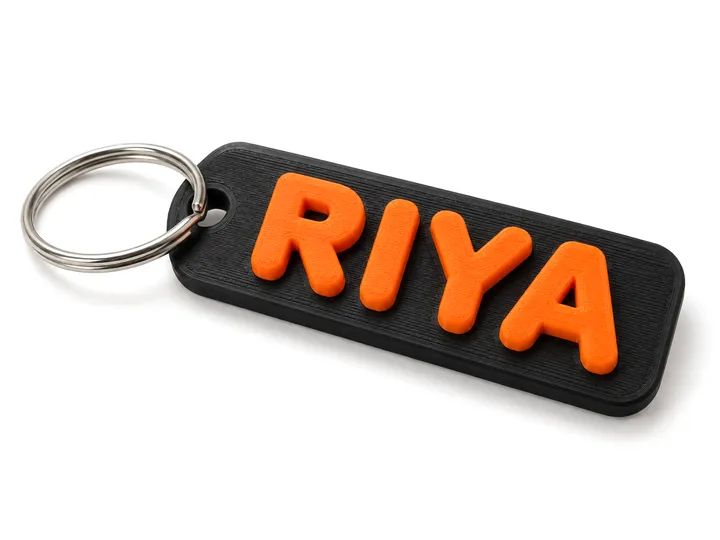 Custom name keychain reading RIYA, orange letters on black